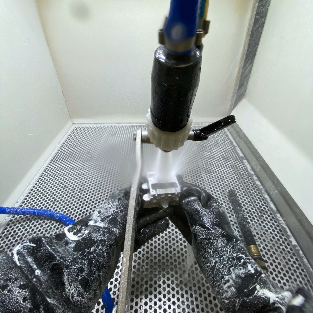 CNC Vapour Honing An operator holding a precisely finished metal part after it has been through the vapour honing process.